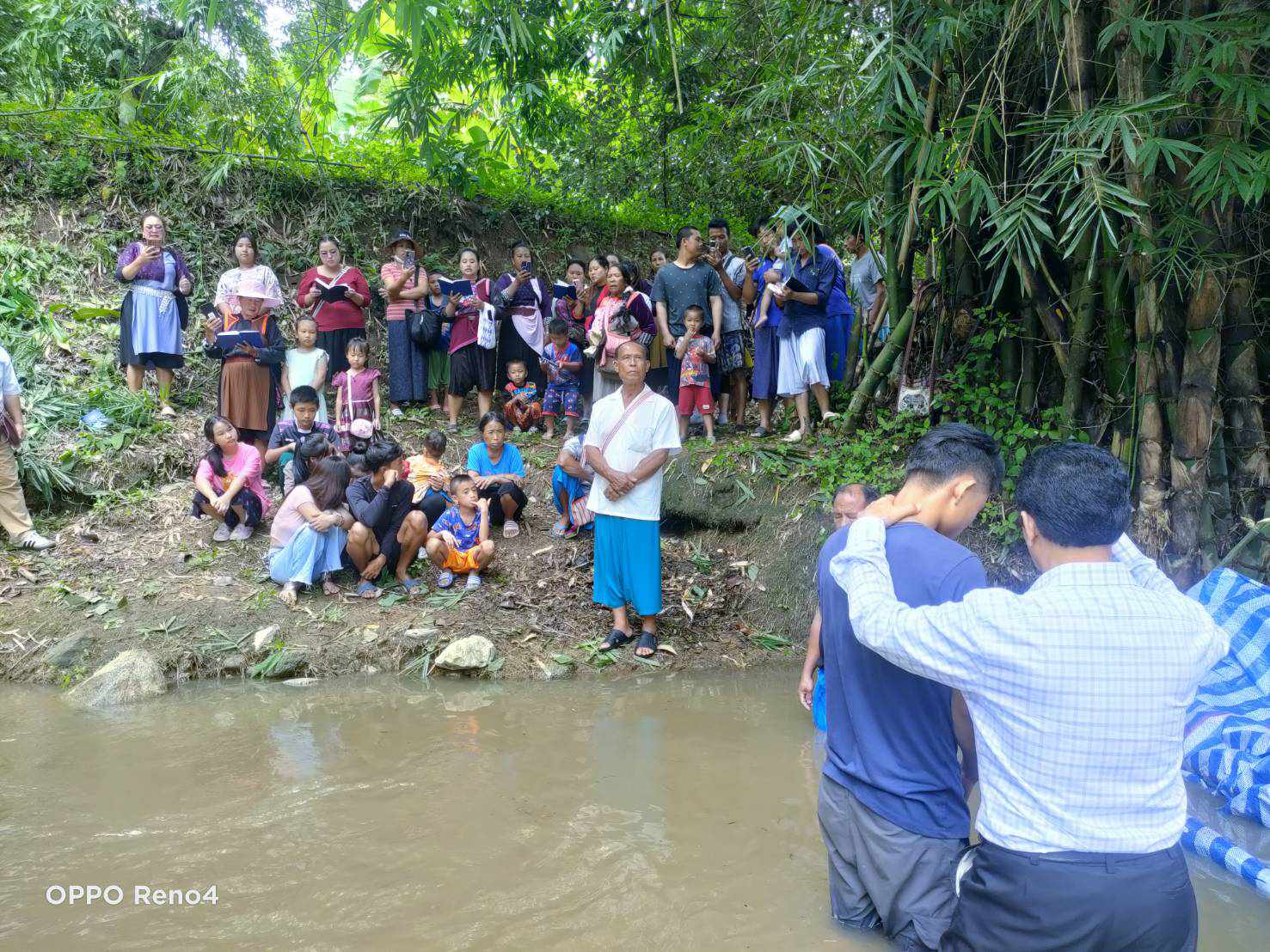 A river baptism in Northern Thailand, with a congregation gathered on the bank