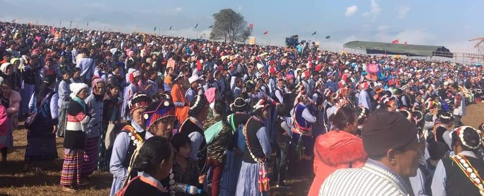 A huge crowd of Lisu men, women and children in traditional dress and colourful headdresses, filling an open field as far as the eye can see