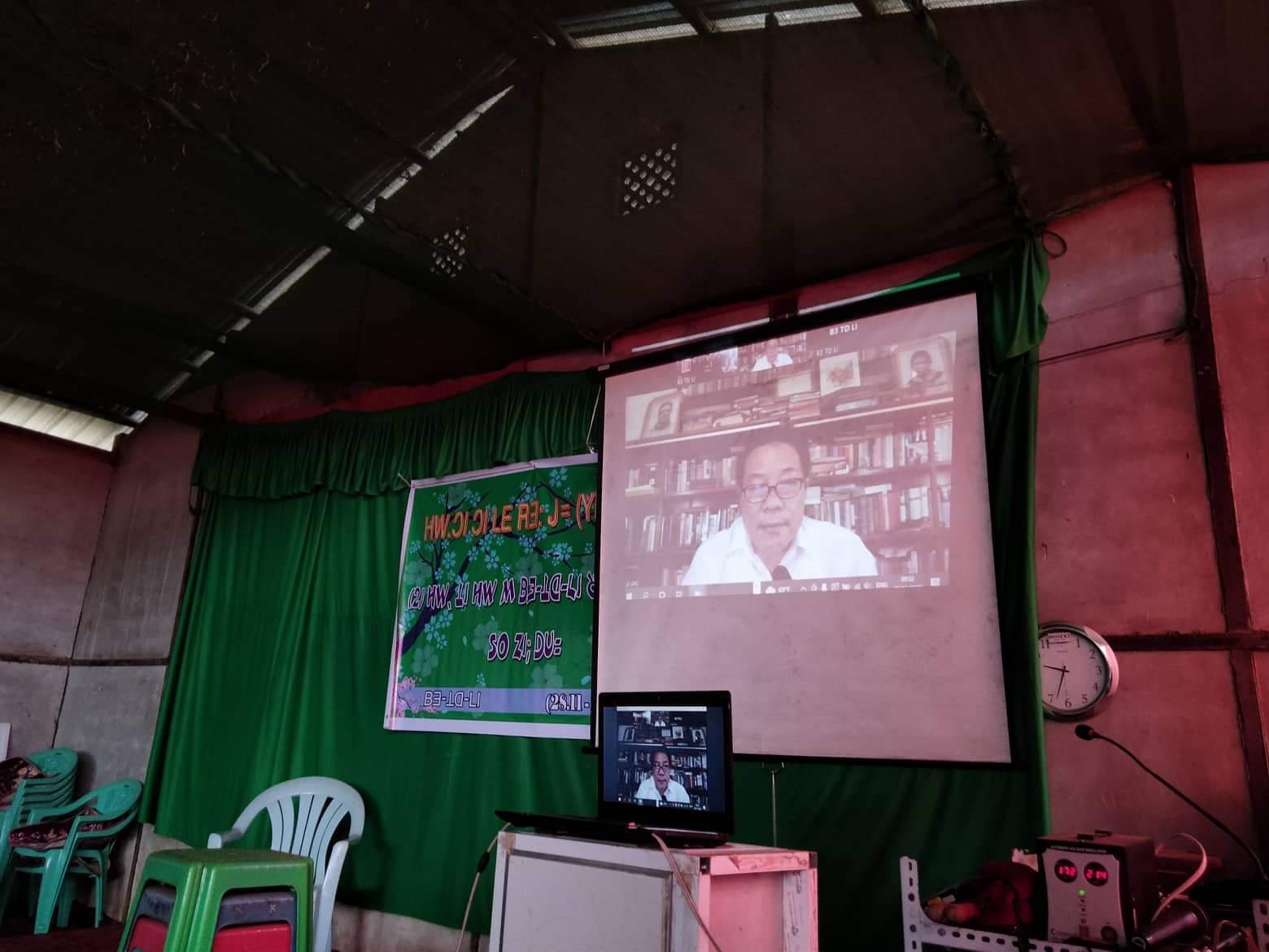 Stephen teaching a Bible class by video during Covid, projected on a screen at the front of a village classroom
